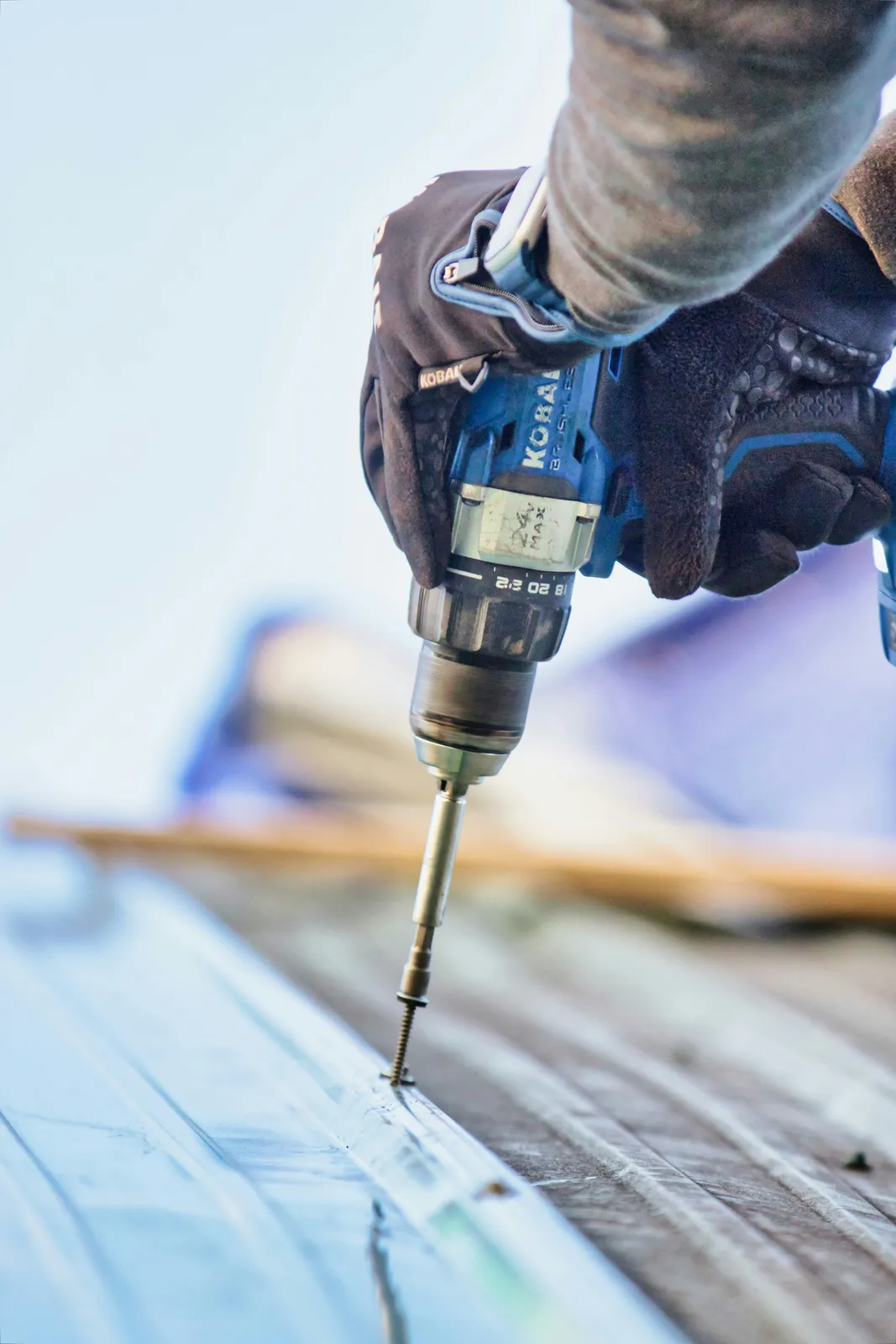 Screw driven into a metal roof panel by a roofer